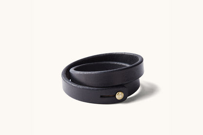 A double wrap black leather wristband with brass closure.